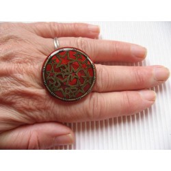 Large graphic ring, bronze stars, on a red resin background