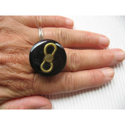 Fancy ring, bronze infinity charm, on black resin background