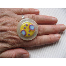 Large ring, multicolored cabochon on a yellow fimo background, on a pearly white resin background