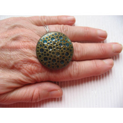 Large graphic ring, bronze stamp with holes, on a blue resin background