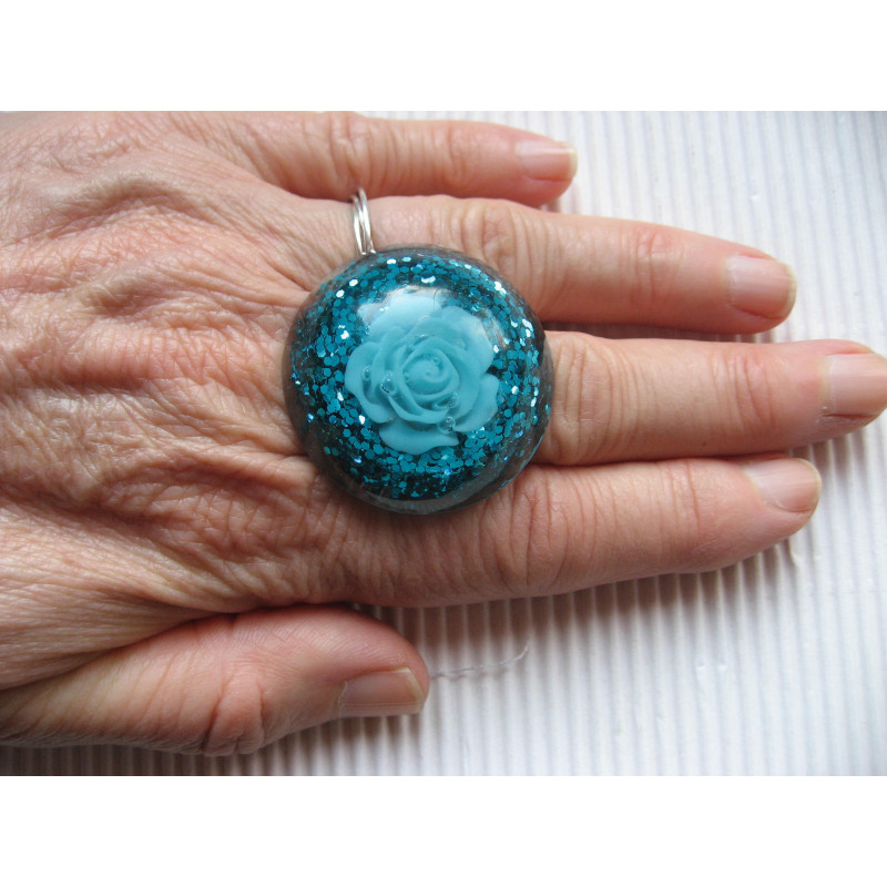 Large cabochon ring, turquoise flower, on turquoise resin background