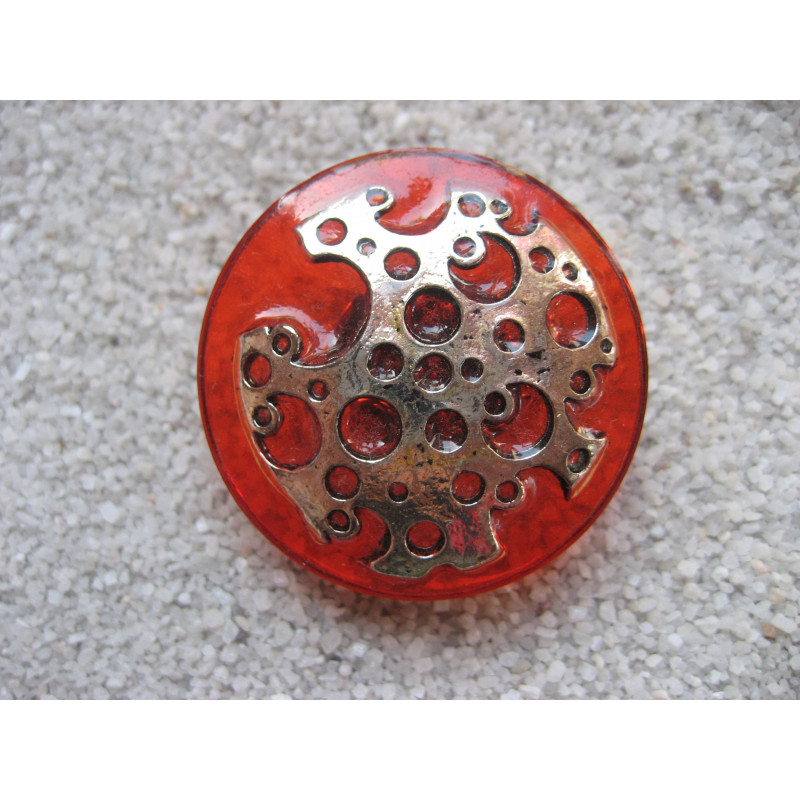 Large graphic ring, perforated silver print, on orange resin background