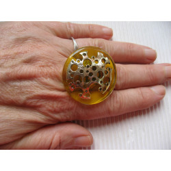 Large graphic ring, perforated silver stamp, on a yellow resin background